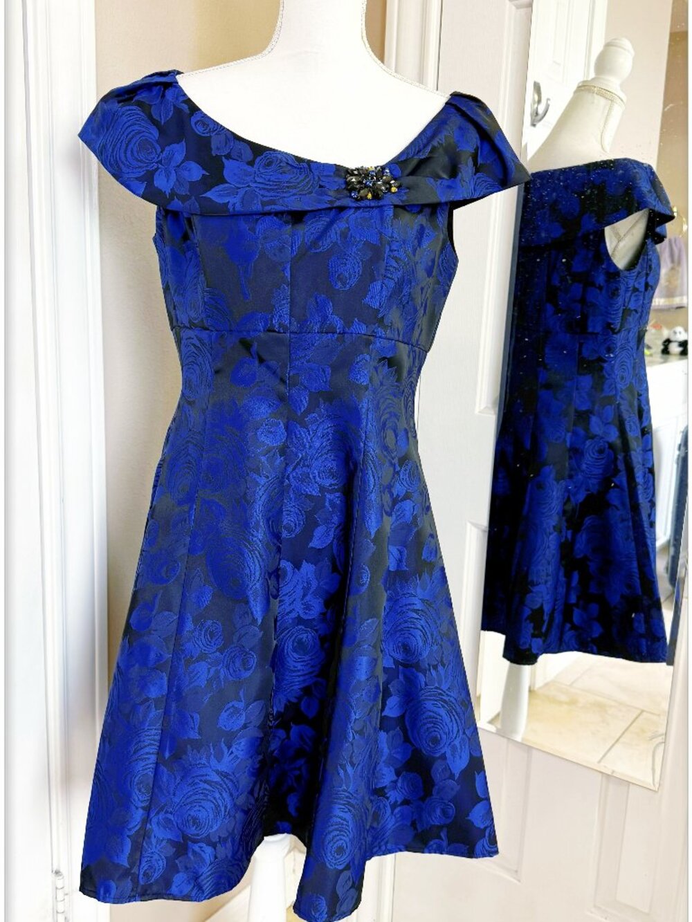 Off-the-shoulder Floral jacquard cocktail dress features jeweled brooch accent